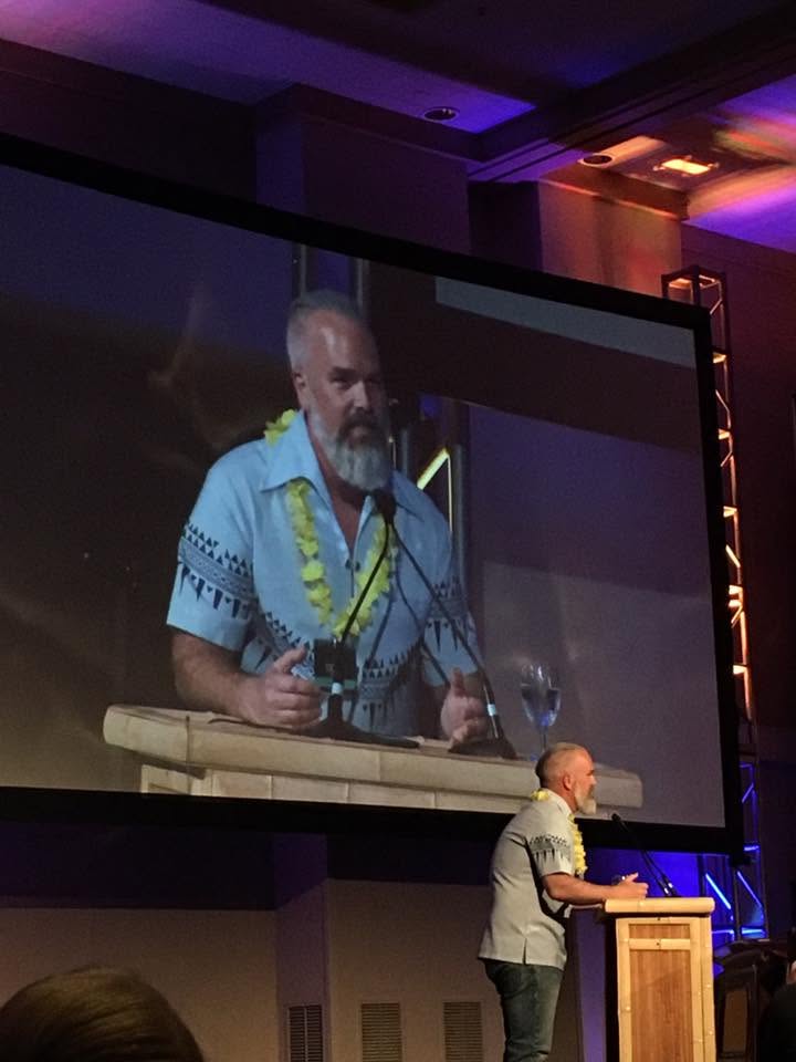 Colin How speaking at a podium in Hawaii